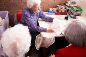 Enid showing the art of needle work to other residents at Yukana